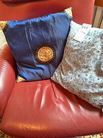 Blue silk pillow and part of gray pillow on red chair