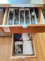 Drawer with stainless flatware in trays and lower drawer of linens