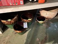 Four green and brown drip-glazed ceramic planters on floor