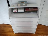 Front view of white painted dresser with three drawers and top shelf