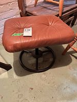 Full view of brown leather swivel ottoman showing seat and metal base
