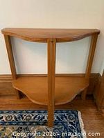 Front view showing demilune shape, two tiers, reeded legs