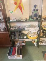 Front view of green painted wood shelving unit showing three shelves and distressed finish