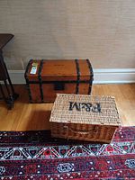 Wood trunk chest and wicker hamper basket positioned on floor