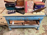Front view of blue distressed wood work table with drawers and lower shelf