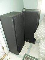 Two black rectangular Mitsubishi speakers standing side by side near a couch