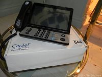 Ultratec CapTel 2400iBT phone displayed on top of its original box with handset.