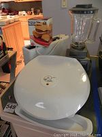 White George Foreman GR30 grill with closed lid, logo, and cord visible, Burger Thing box in background.