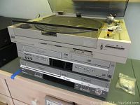 Front view of the stacked electronics showing AIWA turntable on top, Panasonic DVD recorder and VHS to DVD recorder beneath.