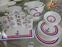 Overview photo of the full set showing bowls, plates, serving trays, and cups with nautical anchor motif and red and blue rings on white ceramic.