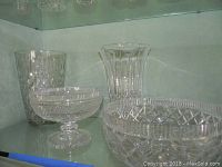 Four Waterford crystal pieces: footed bowl, footed vase, compote, and tumbler with detailed cut designs.