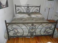 Full view of bed assembled with bronze finished metal headboard, footboard, and frame showing intricate scrollwork and bronze patina.