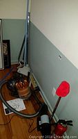 Dyson DC39 vacuum with attachments, hose, and manual on floor next to wall