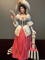 Front view of Mrs. Albee figurine showing full attire, fan and column with bag