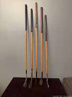 Full view of all five hickory golf clubs standing upright