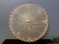 Front view of textured clear glass dome light with pink scalloped edge