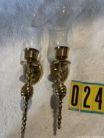 Pair of brass wall sconces with glass shades and measuring card for scale