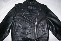 Front view of black leather motorcycle jacket showing lapels, pockets, belt