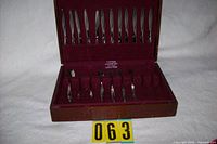Flatware set in burgundy-lined wooden Eureka chest, knives in lid, other pieces in base
