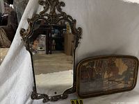 Front view of ornate mirror beside landscape picture