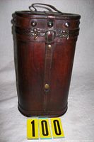 Front view of cylindrical wood and leather wine bottle holder showing hardware and handle
