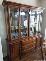 Front view of full buffet and hutch showing wood finish, glass doors, hardware