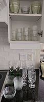 cabinet shelf and countertop view showing variety of glasses and bowls