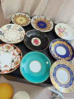 Group shot of all nine plates on ottoman showing patterns and colours