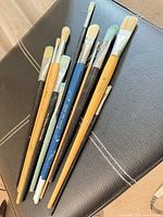All ten assorted paint brushes grouped on seat