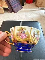 side view showing cobalt blue base, romantic figure panels and gold handle