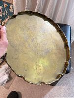 Top view of brass tray showing scalloped edge and engraved scene