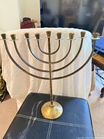 Full view of brass nine-branch Menorah standing on base