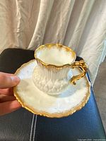 Cup on saucer showing overall design, gold gilt, scalloped edges
