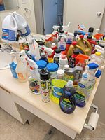 Overview of countertop filled with various cleaning supplies bottles, sprays and cans