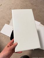 Front view of one white stretched canvas panel held in hand