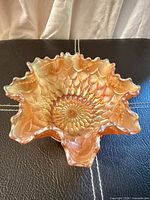 Top view of iridescent marigold carnival glass bowl showing sunflower pattern and ruffled edge