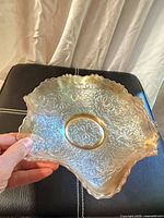 Top view of marigold carnival glass dish showing floral pressed pattern and scalloped edge