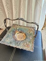 Top view of square silver-plated cake basket showing floral embossing and handle