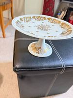 Side view of pedestal cake stand showing gold floral top and pedestal base