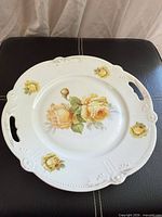 Top view of round porcelain platter showing yellow rose decals, scalloped rim and handles