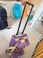 Purple rolling duffel with handle extended showing color, trim, and wheels