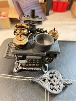 Stove assembled with brass tea set, cast iron pot and trivet visible
