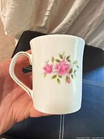 Side view showing pink roses motif, handle, white body