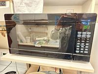 Front view of RCA microwave showing control panel, LED clock at 13:51, and RCA logo