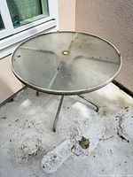 Full view of round glass patio table showing top surface and frame