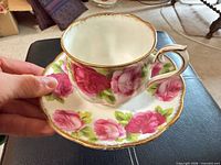 Teacup on saucer showing exterior rose pattern and gold trim