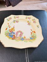 Front view of square scalloped plate showing full floral pattern and gold trim