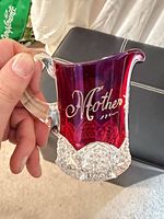 Front view showing etched “Mother” on ruby overlay and clear faceted base