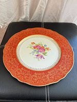 Front of plate showing floral centre, red border, gold trim