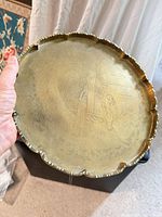 Front view of brass tray showing scalloped rim and engraved scene